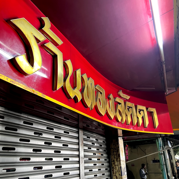 Classic signage on Thanon Phra Athit. 3D gold lettering on a red sign.